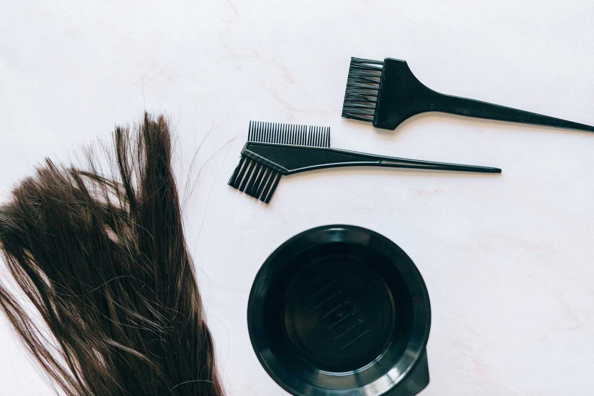 Haircut tools and brush with hair locks on a white surface.